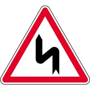 Panneau de danger annonçant une succession de virages dont le premier est à gauche.