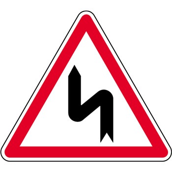 Panneau de danger annonçant une succession de virages dont le premier est à gauche.